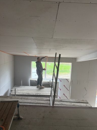 Large Bespoke Stairwell A person using scaffolding to work on a ceiling in an unfinished room.